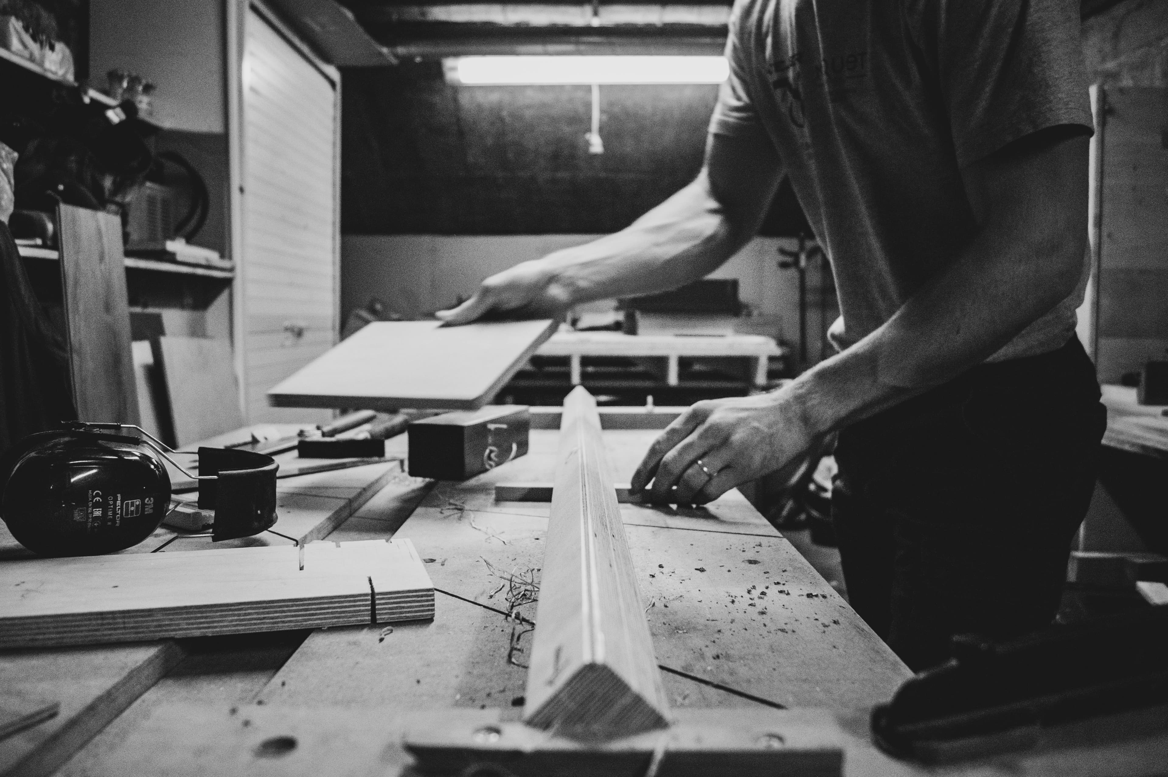 Craftsperson measuring timber at a workshop bench