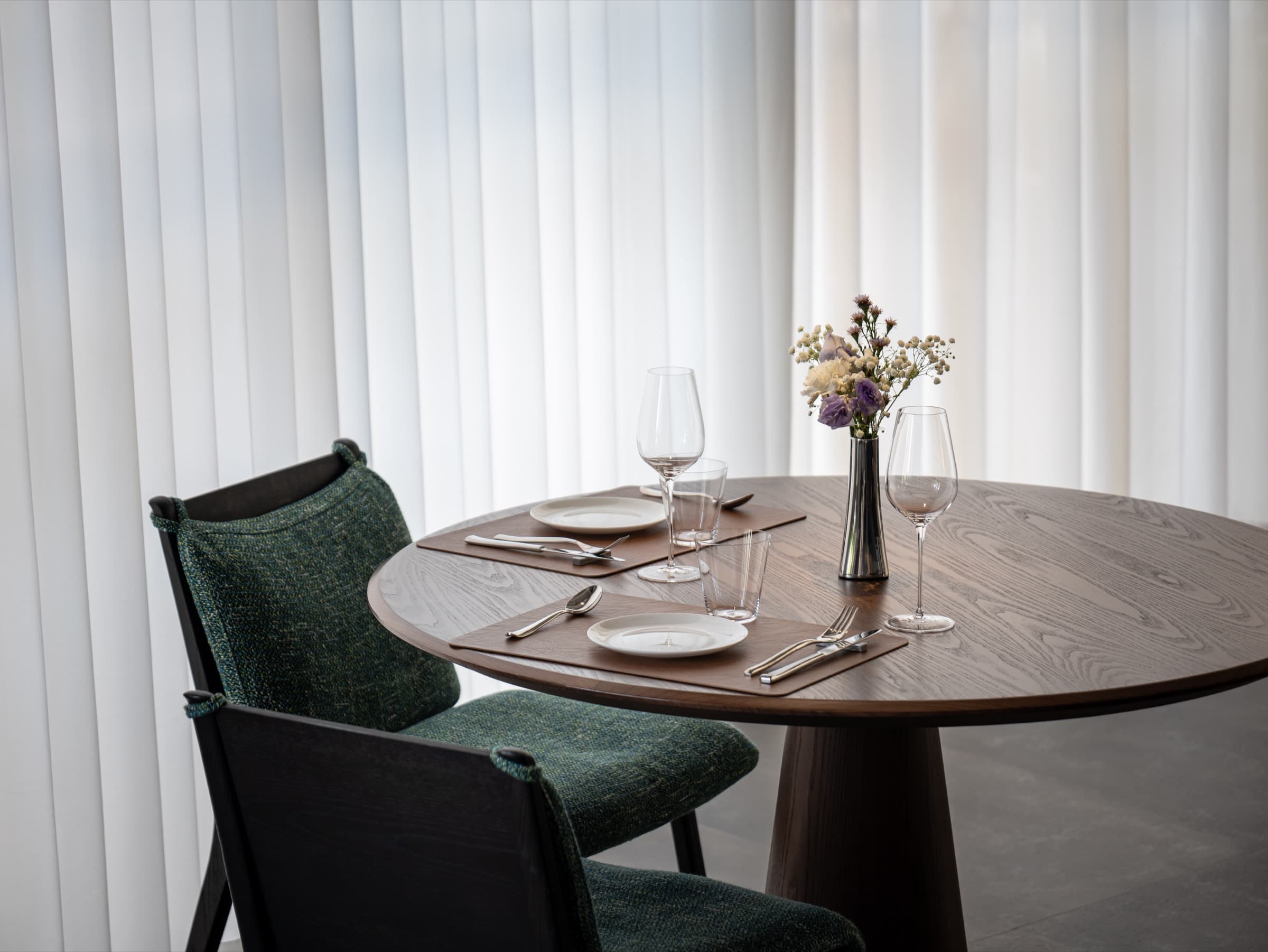 Round timber table set for two beside sheer curtains at Sense Bistro