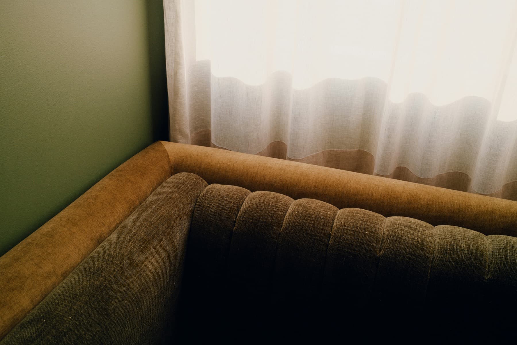 Curved upholstered sofa beside a softly lit window